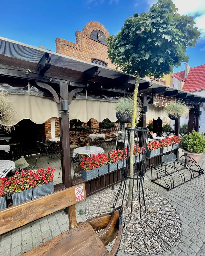 Ogródek z kwiatami i markizami przed ceglaną fasadą